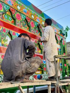Two men painting a wall with colorful designs.