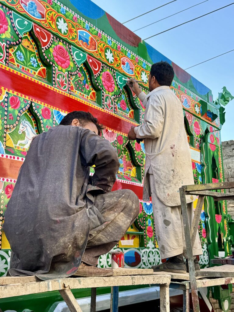 Two men painting a wall with colorful designs.