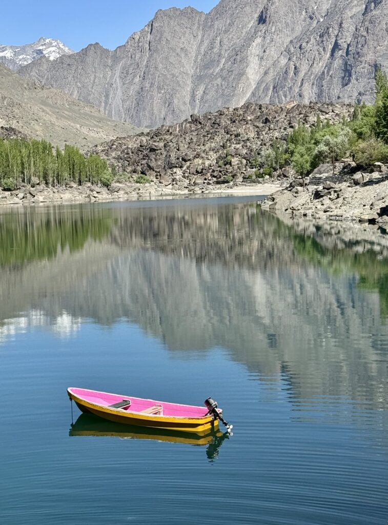 A yellow and pink boat floating on top of water.