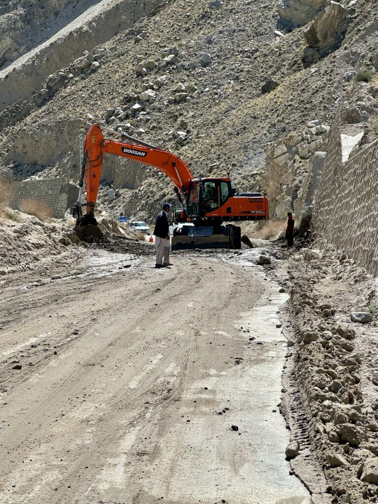 A man standing in front of an orange and black excavator.