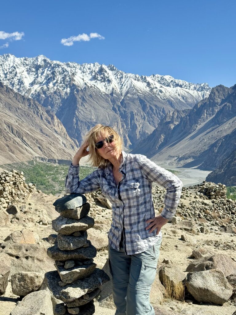 A woman standing next to rocks on top of a mountain.