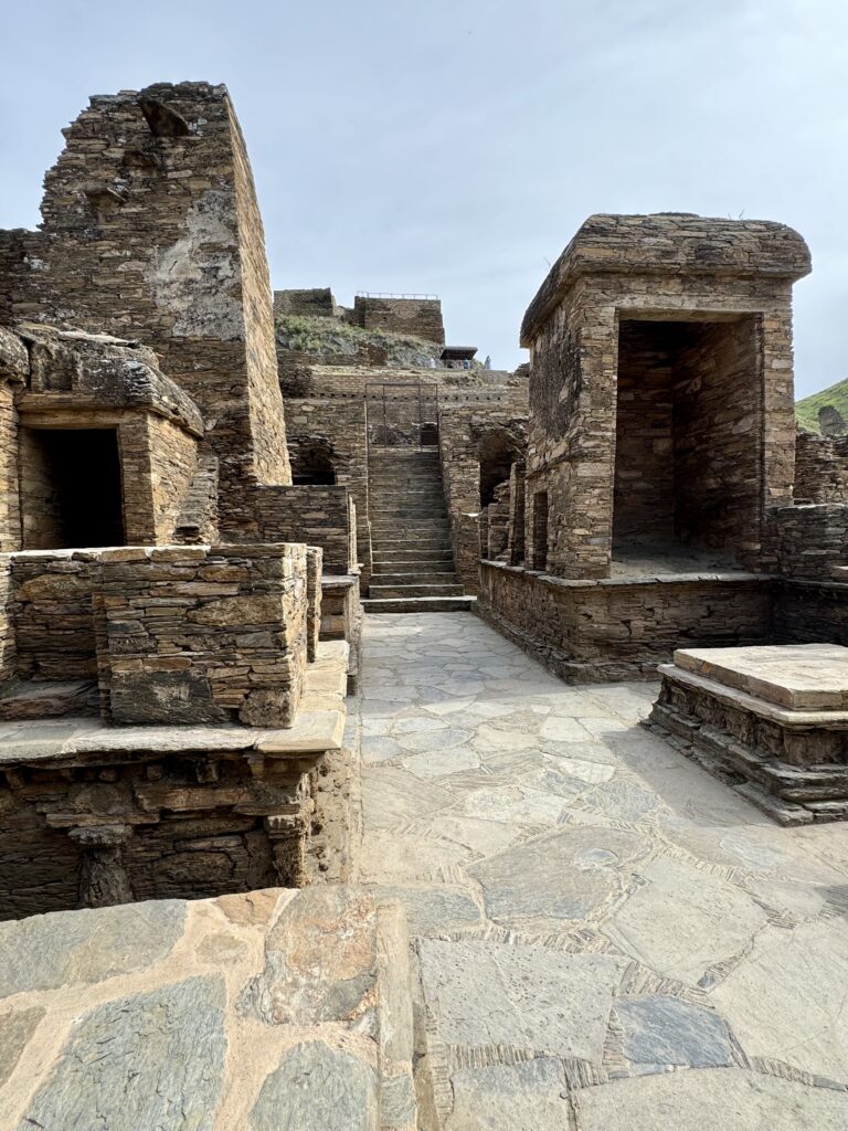 A stone courtyard with steps and pillars leading to the top.