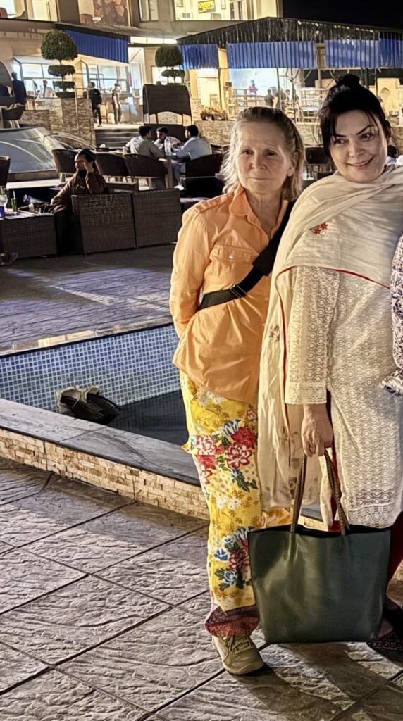 Two women standing next to each other on a sidewalk.