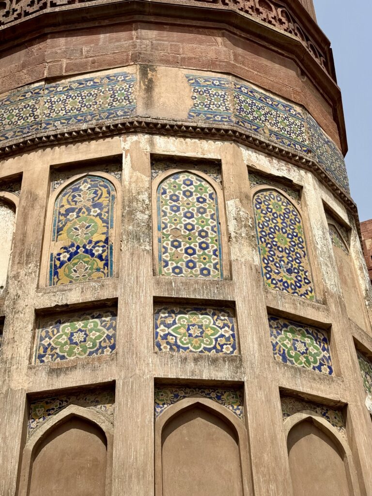 Intricate tilework on a historic curved wall with arched windows.